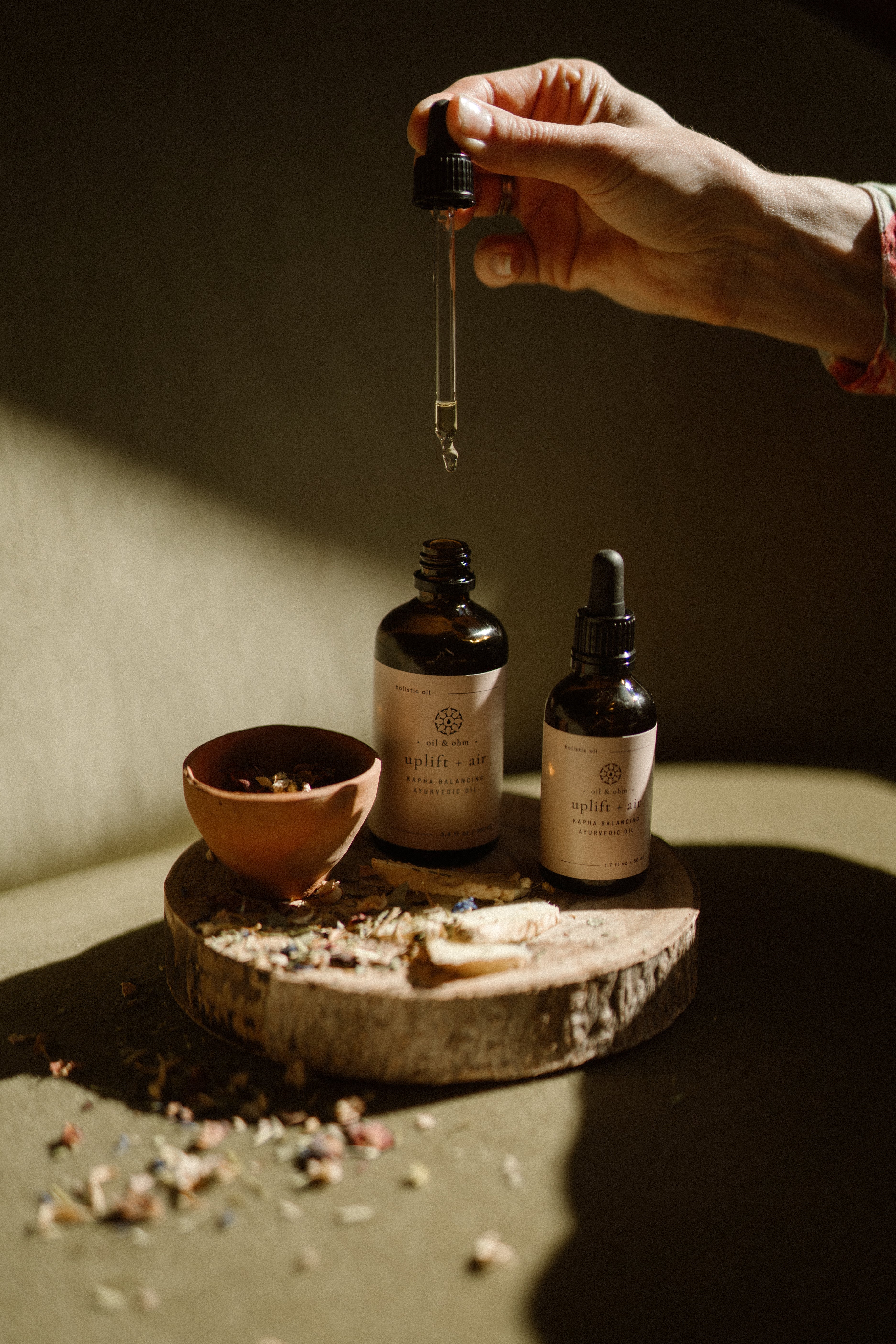 Bottles of Oil&Ohm Kapha Balancing Body Oil with hand dripper