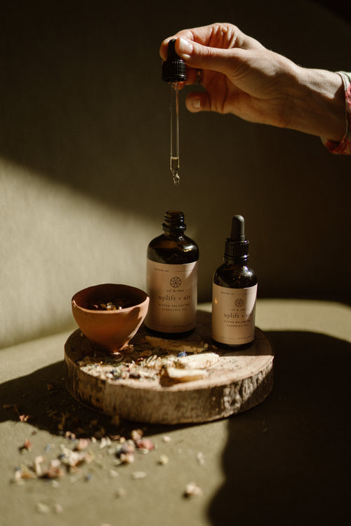 Bottles of Oil&Ohm Kapha Balancing Body Oil with hand dripper